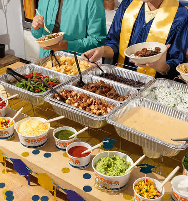 QDOBA Mexican buffet-style catering setup at a graduation party, with trays of proteins, queso, rice, beans, salsa, and guacamole—ideal for spring and summer events like graduation parties, school celebrations, and backyard gatherings in Wisconsin, Illinois, and Iowa.